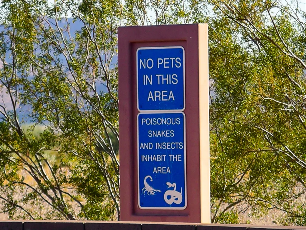 Posted no-pets sign in a wooded outdoor area.