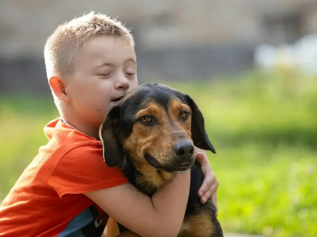 Child hugging a dog outdoors.
